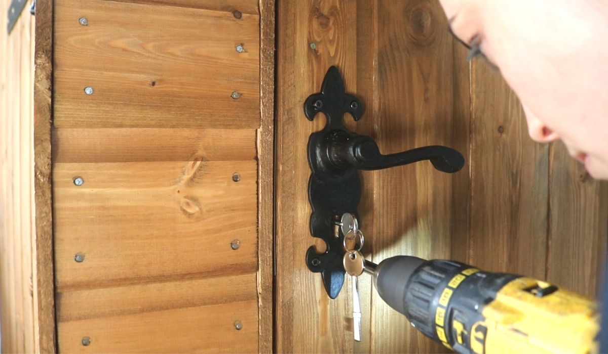 a women installing a handle on a shed