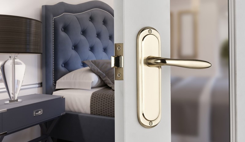 Mocho lever latch door handle polished solid brass on a bedroom door
